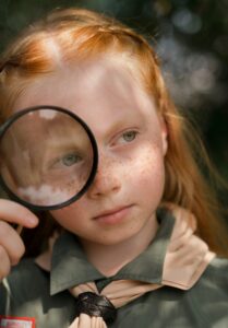 girl looking through magnifying glass
