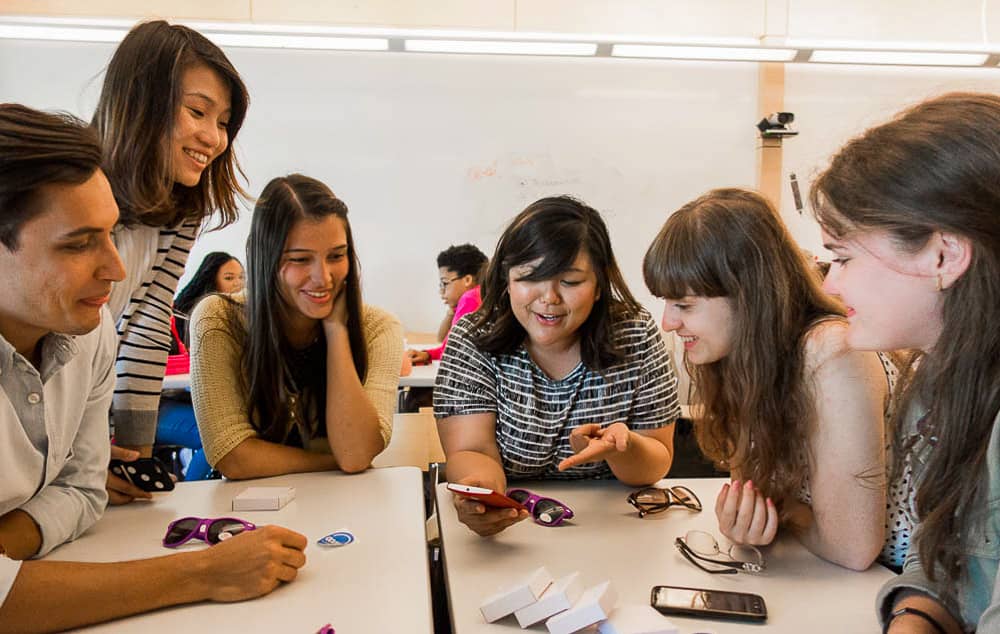 girls at table with woman using a phone